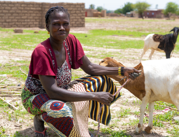 kvinna med en get i bakgrunden, burkina faso.