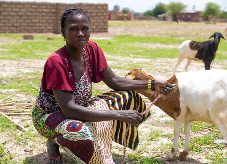 kvinna med en get i bakgrunden, burkina faso.