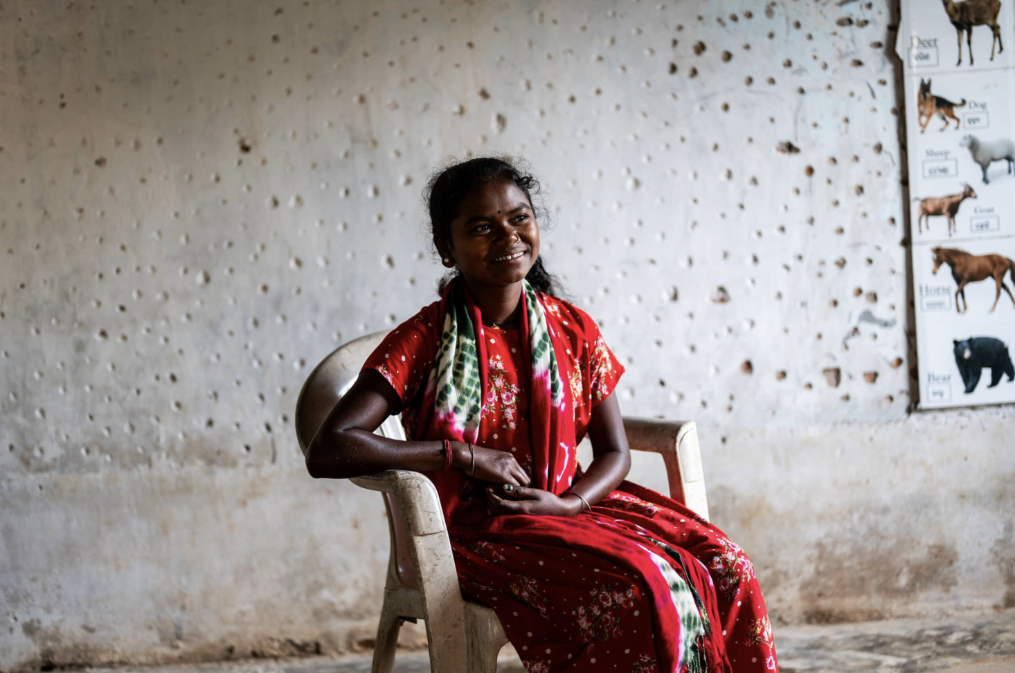 Indisk flicka sitter på en stol, ler